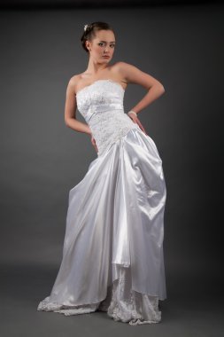 Beyaz bir elbise içinde gelin. Stüdyo portre gri arka plan üzerinde