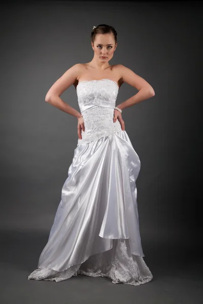 Bruid in een witte jurk. studio portret op grijze achtergrond — Stockfoto