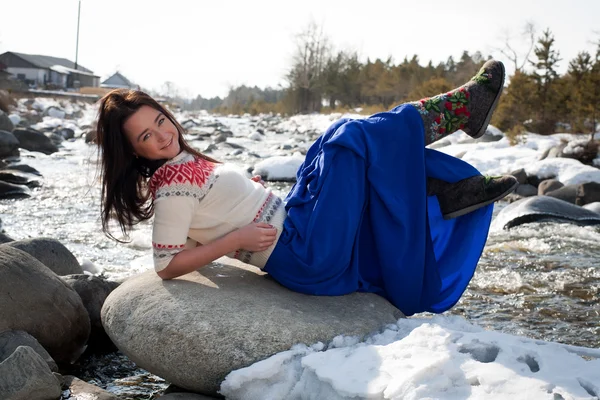 Junges Mädchen sitzt am Ufer des Flusses Schnee — Stockfoto