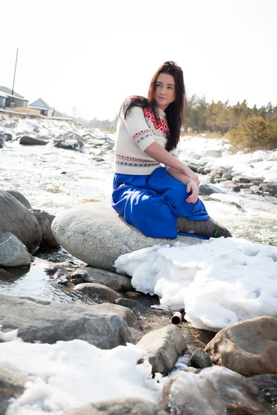 Młoda dziewczyna siedzi na brzegu rzeki śnieg — Zdjęcie stockowe