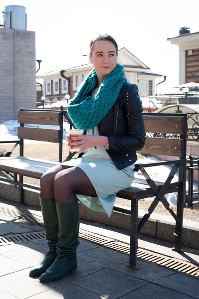 Meisje met een kopje koffie zittend op een bankje in de stad — Stockfoto