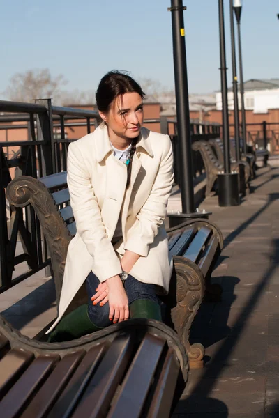 Meisje, zittend op een bankje in de stad — Stockfoto