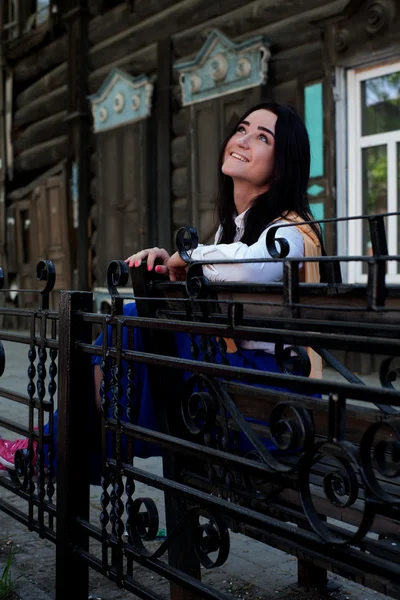 Beautiful girl on the background of old wooden houses — Stock Photo, Image