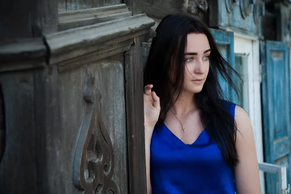 Beautiful girl on the background of old wooden houses — Stock Photo, Image