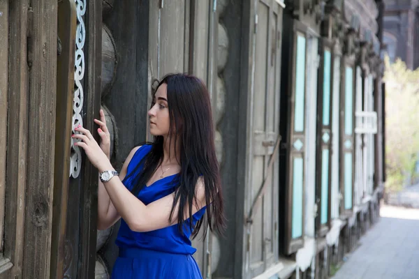 Schönes Mädchen auf dem Hintergrund alter Holzhäuser — Stockfoto