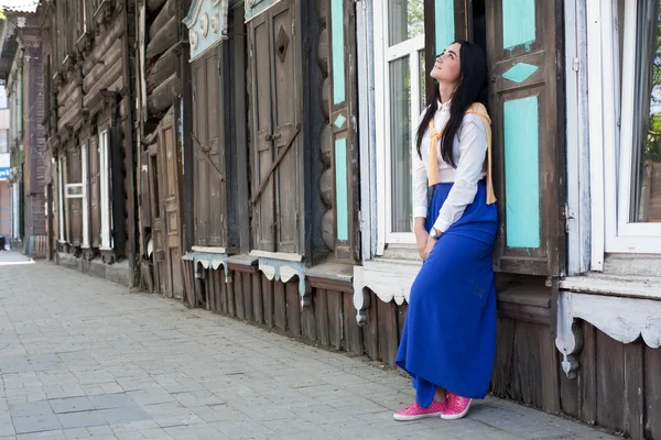 Mooi meisje op de achtergrond van oude houten huizen — Stockfoto