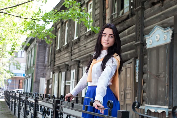 Schönes Mädchen auf dem Hintergrund alter Holzhäuser — Stockfoto