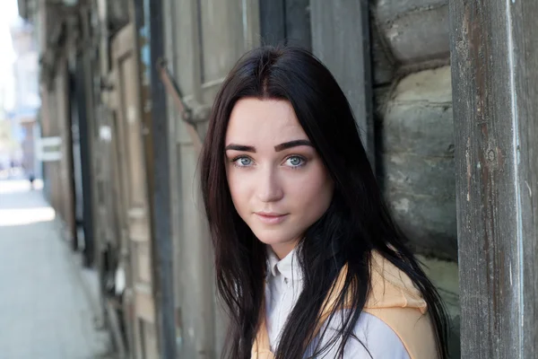 Porträtt av en ung flicka på en bakgrund av det gamla timmerhuset — Stockfoto