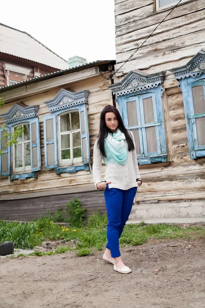 Young girl on a background of the old wooden house — Stock Photo, Image