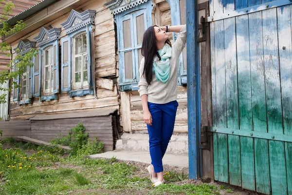 Young girl on a background of the old wooden house — Stock Photo, Image