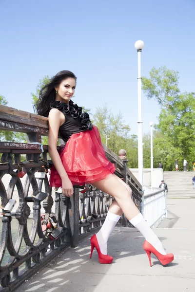 Девушка в ярком платье и носках стоит у железнодорожного моста — стоковое фото