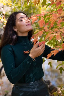 Genç esmer sonbahar parkında yürüyor.