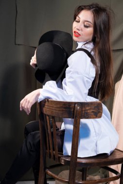 Uzun saçlı, şapkalı, geniş pencereli bir odada poz veren bir kız.