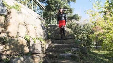 Kırmızı elbiseli kız eski bir binanın taş basamaklarından iniyor.