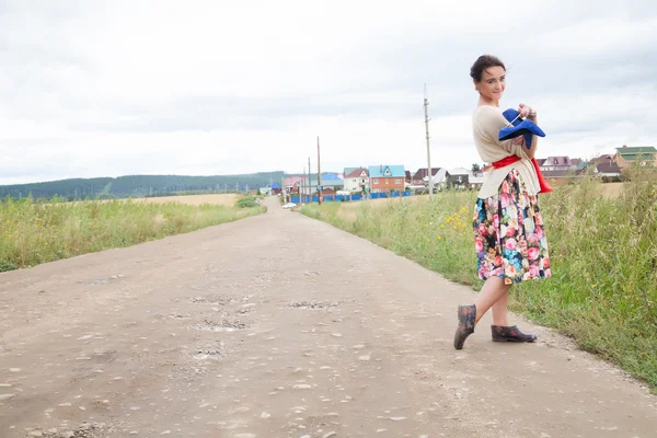 Girl in galoshes on a country road — Stock Photo, Image