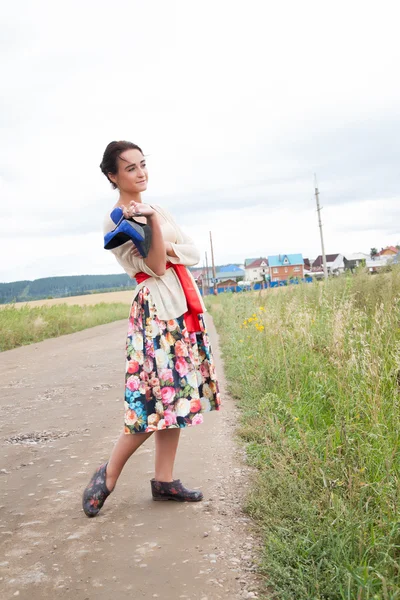 Girl in galoshes on a country road — Stock Photo, Image