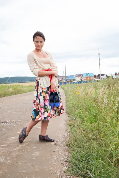 Girl in galoshes on a country road — Stock Photo, Image