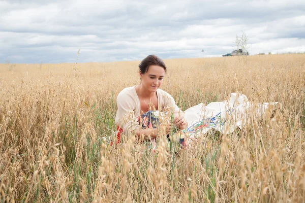 Ragazza seduta in un campo di spighe di grano — Foto Stock