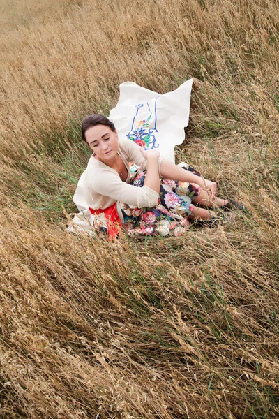 Dziewczyna siedzi w polu pszenicy uszy — Zdjęcie stockowe