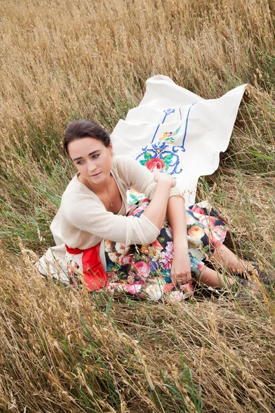 Mädchen sitzt in einem Feld aus Weizenähren — Stockfoto