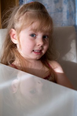 Çilli küçük kız beyaz bir masada oturuyor.