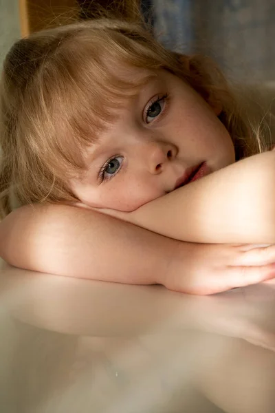 Mała Dziewczynka Piegami Siedzi Przy Białym Stole — Zdjęcie stockowe