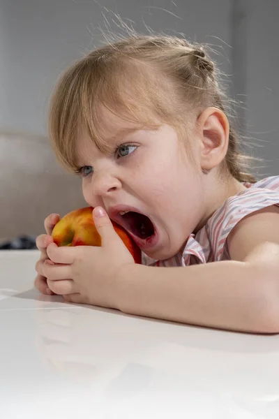 Petite Fille Avec Une Grosse Pomme Rouge Est Assis Table — Photo