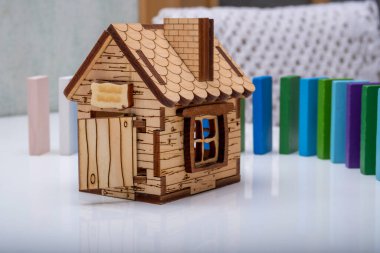 Renkli bir çitin arkasındaki ahşap evin modeli.