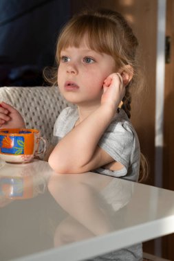 Kız masaya oturur ve bir kupadan dondurma yer.