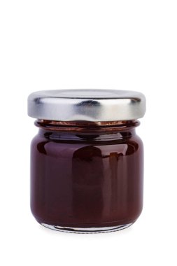 Beyaz zemin üzerinde erik reçeli olan küçük cam kavanoz.