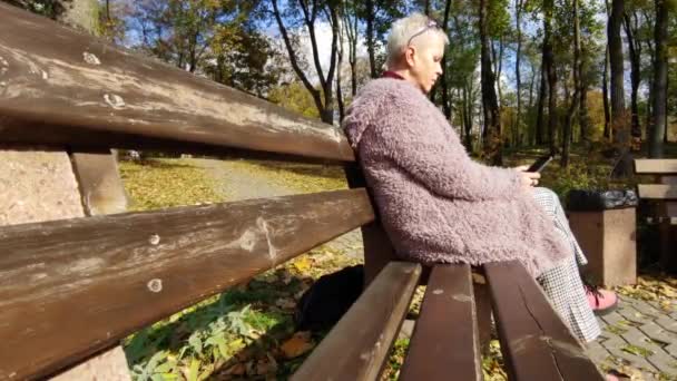 Μια Μοναχική Μεσήλικη Γυναίκα Κάθεται Ένα Παγκάκι Και Διαβάζει Τις — Αρχείο Βίντεο