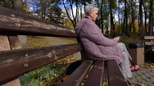 Eine Frau Mittleren Alters Sitzt Auf Einer Bank Und Liest — Stockvideo