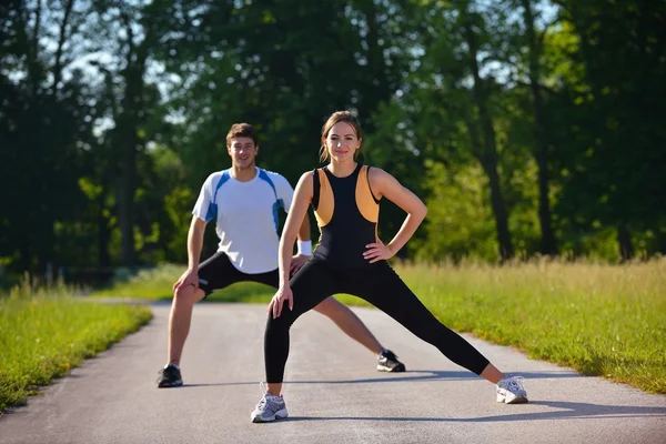 Casal fazendo exercício de alongamento após correr — Fotografia de Stock