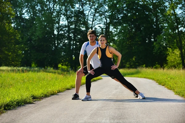 Casal fazendo exercício de alongamento após correr — Fotografia de Stock