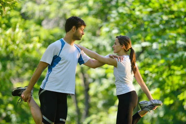 Pareja haciendo ejercicio de estiramiento después de trotar — Foto de Stock