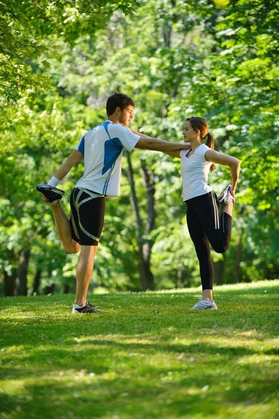 Pareja haciendo ejercicio de estiramiento después de trotar — Foto de Stock