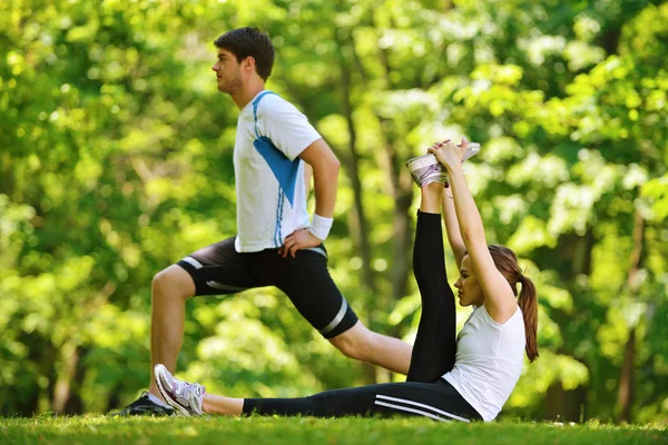 Casal fazendo exercício de alongamento após correr — Fotografia de Stock