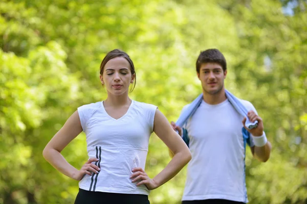 Pareja haciendo ejercicio de estiramiento después de trotar — Foto de Stock