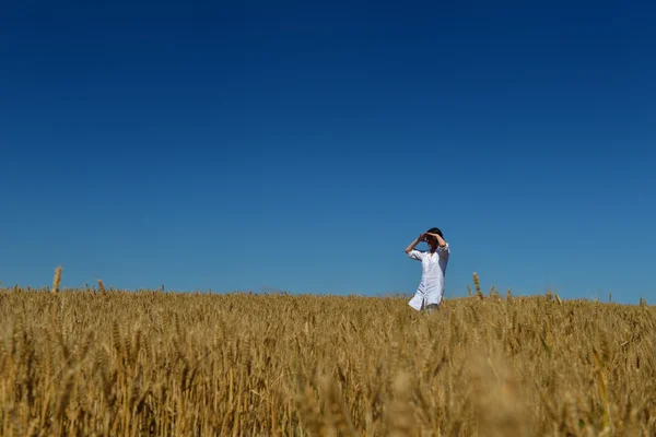 Mladá žena v pšeničném poli v létě — Stock fotografie