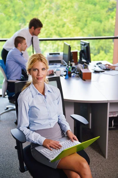 Mujer de negocios con su personal en segundo plano en la oficina — Foto de Stock