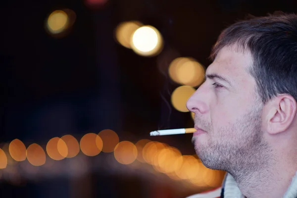 Man smokes a cigaret against a dark background — Stock Photo, Image