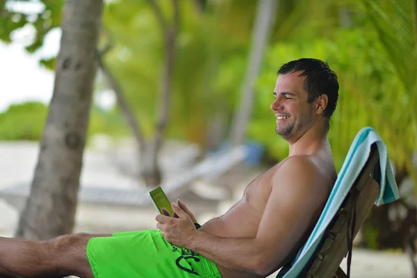 Homem ralaxing e utilizar comprimido na praia — Fotografia de Stock