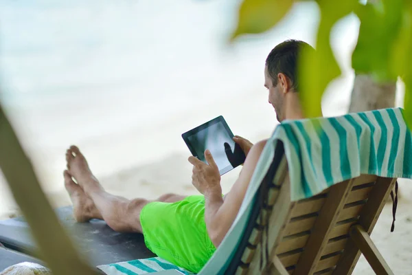 Homem ralaxing e utilizar comprimido na praia — Fotografia de Stock