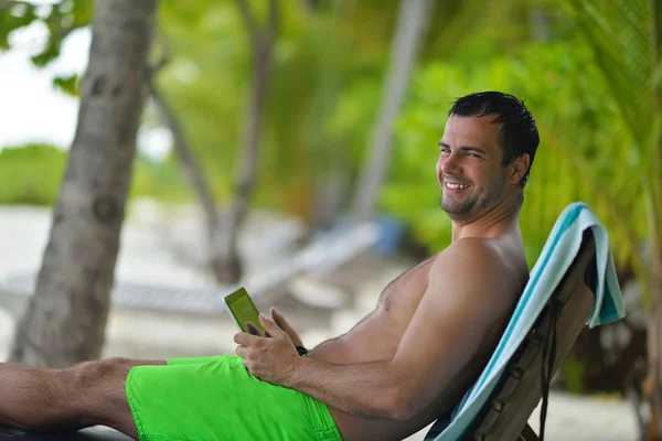 Mann rastet aus und benutzt Tablette am Strand — Stockfoto