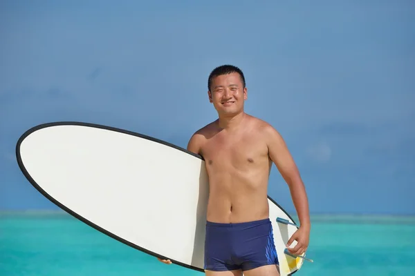 Человек с доской для серфинга на пляже — стоковое фото