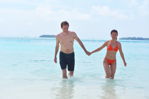 幸せな若いカップルはビーチで楽しんでいます — ストック写真