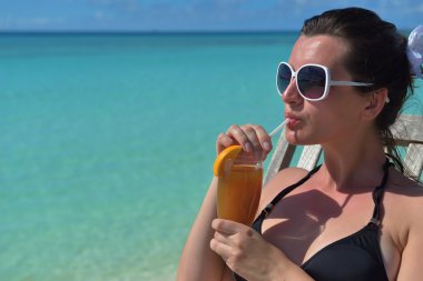 Deniz kenarında bir içkiyle güzel genç kadın