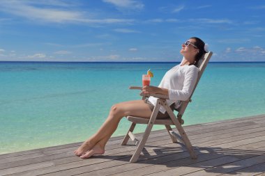 Deniz kenarında bir içkiyle güzel genç kadın