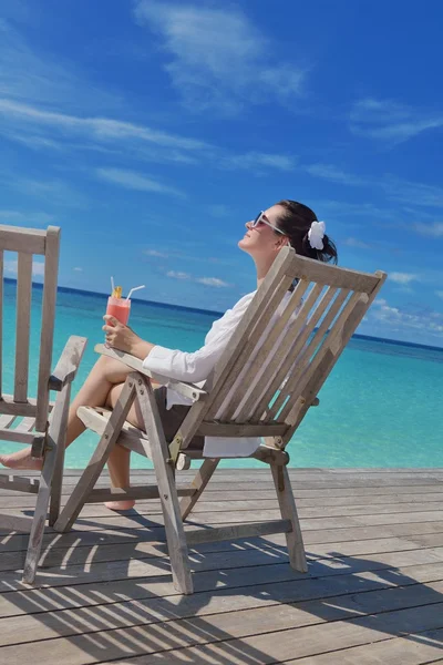 Beautiful young woman with a drink by the sea — Stock Photo, Image