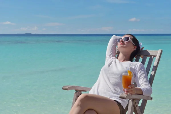 Beautiful young woman with a drink by the sea — Stock Photo, Image